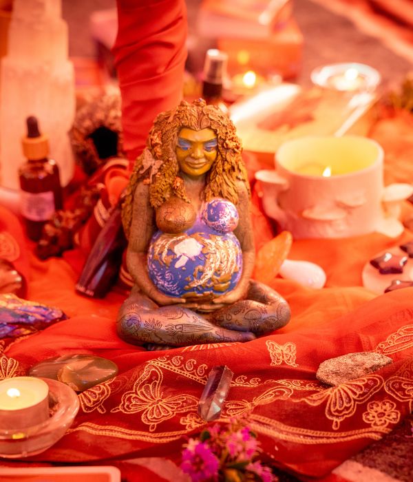 An altar in a tent with candles, crystals, a statue of mother earth holding her womb.