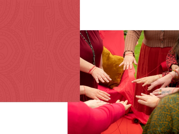 An image of nine hands in a circle with red string linking them all.